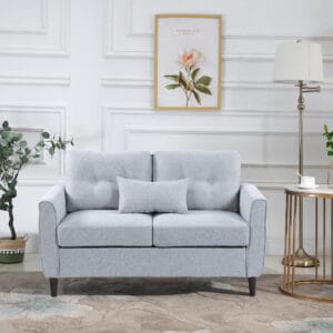 light grey modern chic loveseat with armrests, standing in a room with a white wall and a coffee table