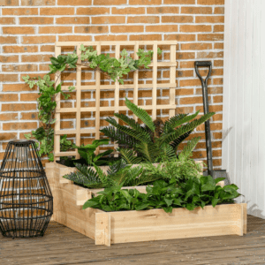 a 3 tier natural wood garden planter with a trellis, up against an outside wall, filled with green leaf plants