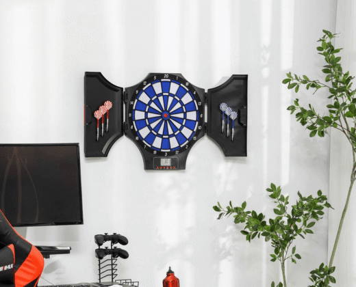an electronic dartboard, with blue and grey segments and 2 sets of darts in a black surrounding case, hanging on a white wall
