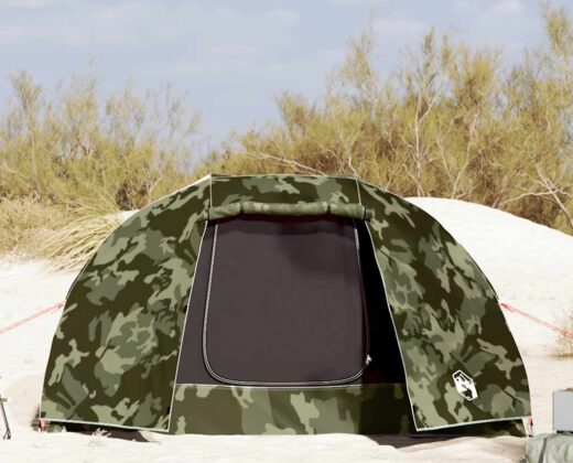 a 5 person fishing tent in a camouflage pattern, on a beach with sand dunes in the background